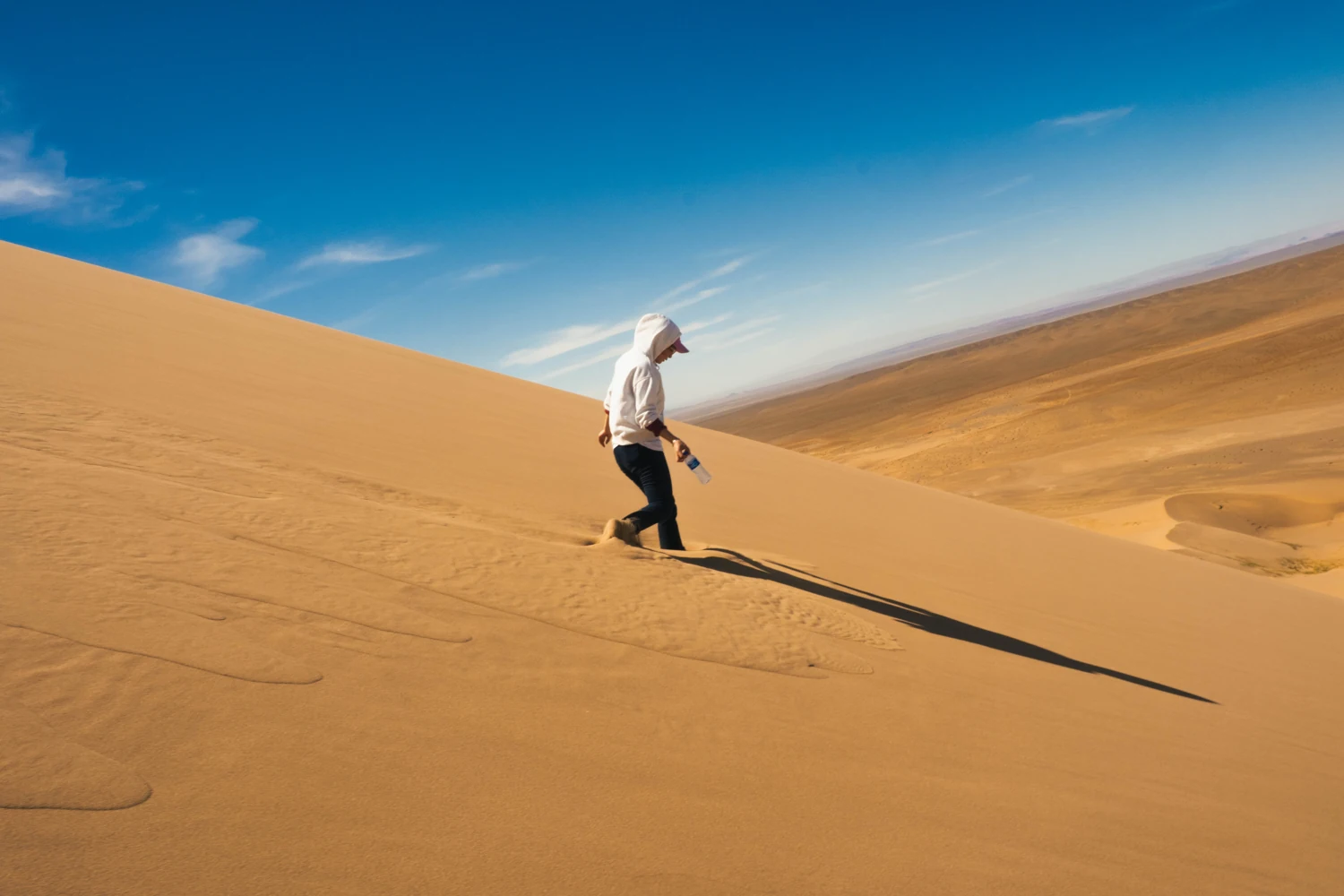 Una persona cammina tra le dune di sabbia