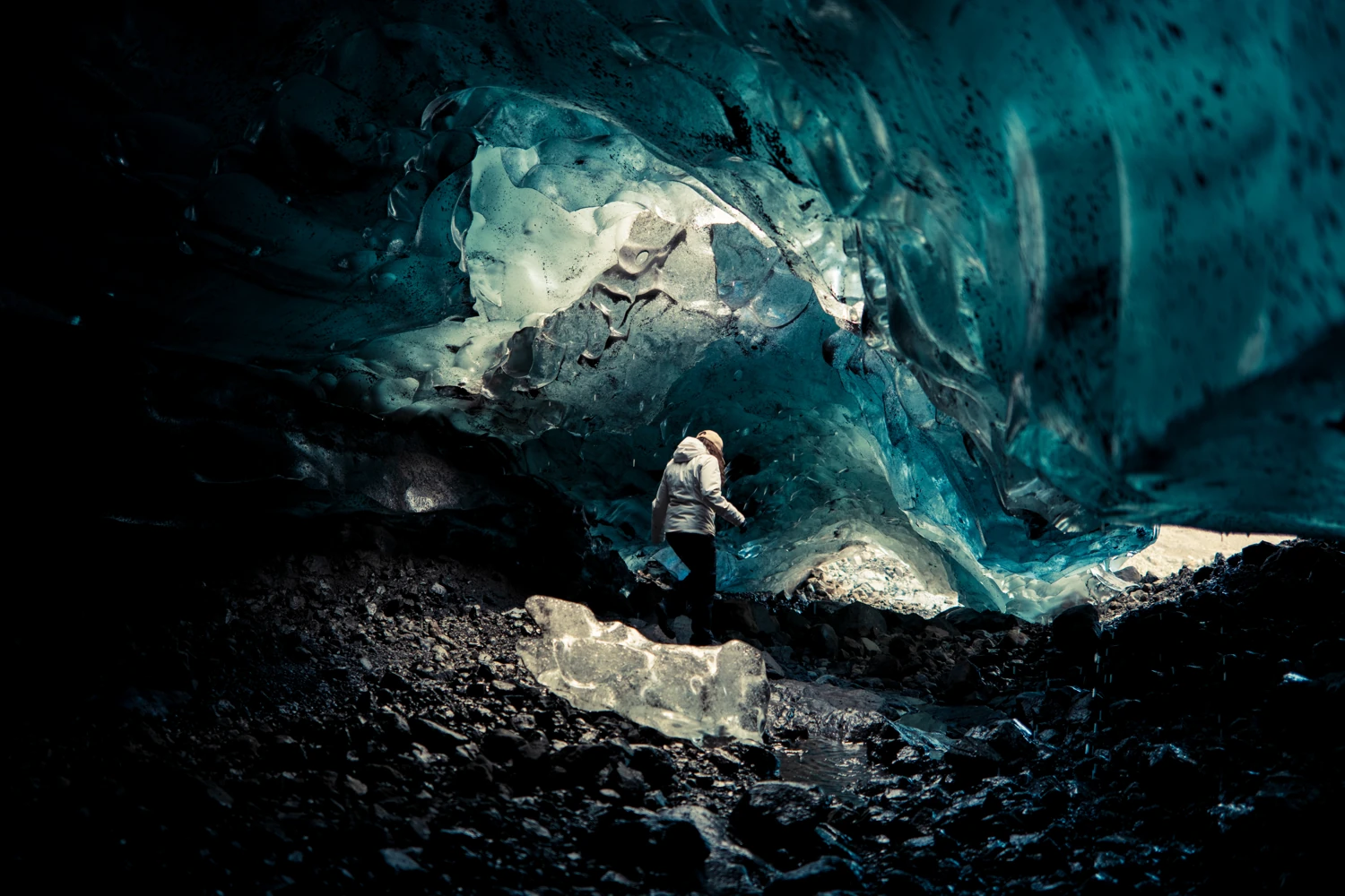Una persona tra le forme e la luce blu di una grotta di ghiaccio islandese