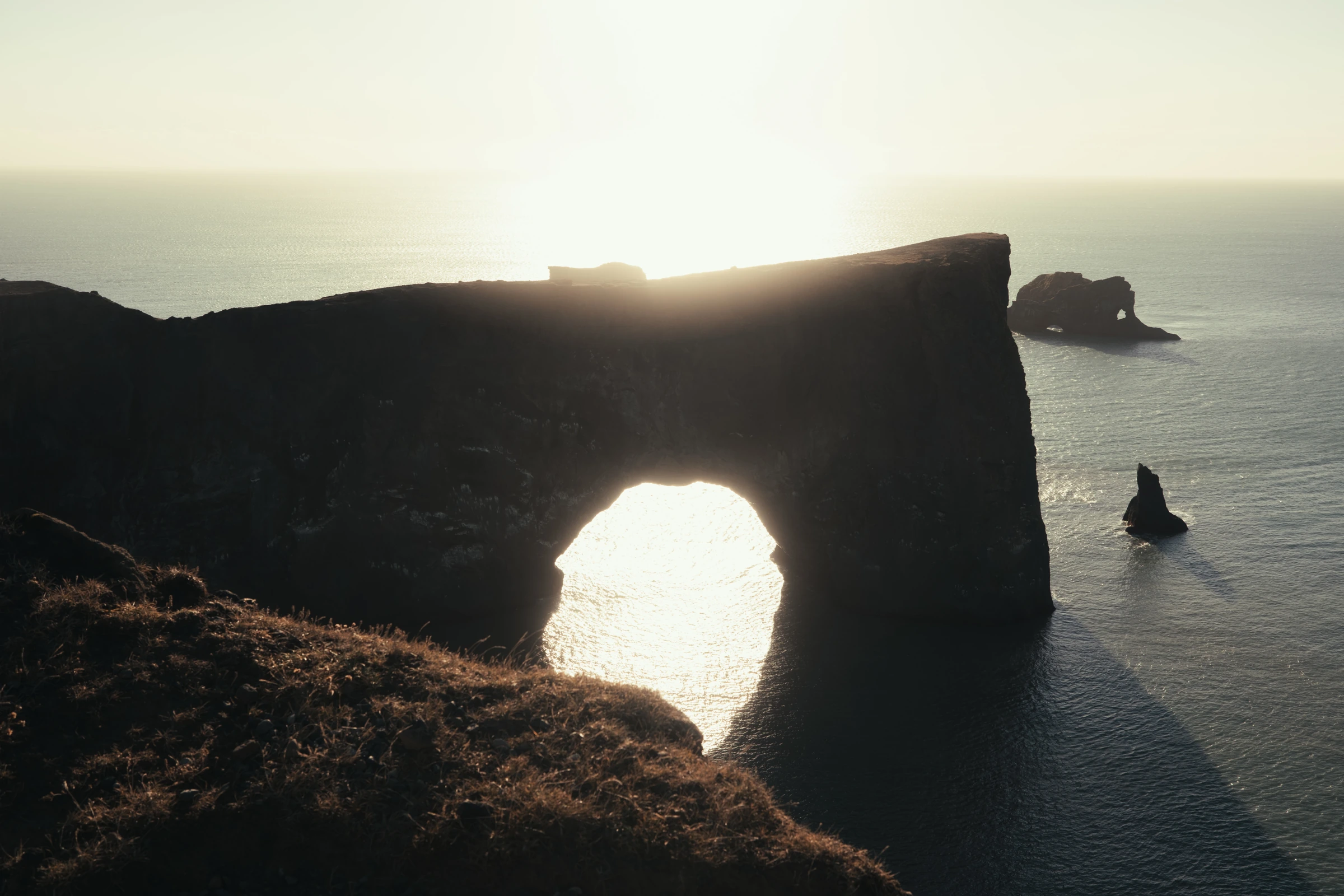 La luce del sole sull’oceano attraversa un arco naturale nella roccia