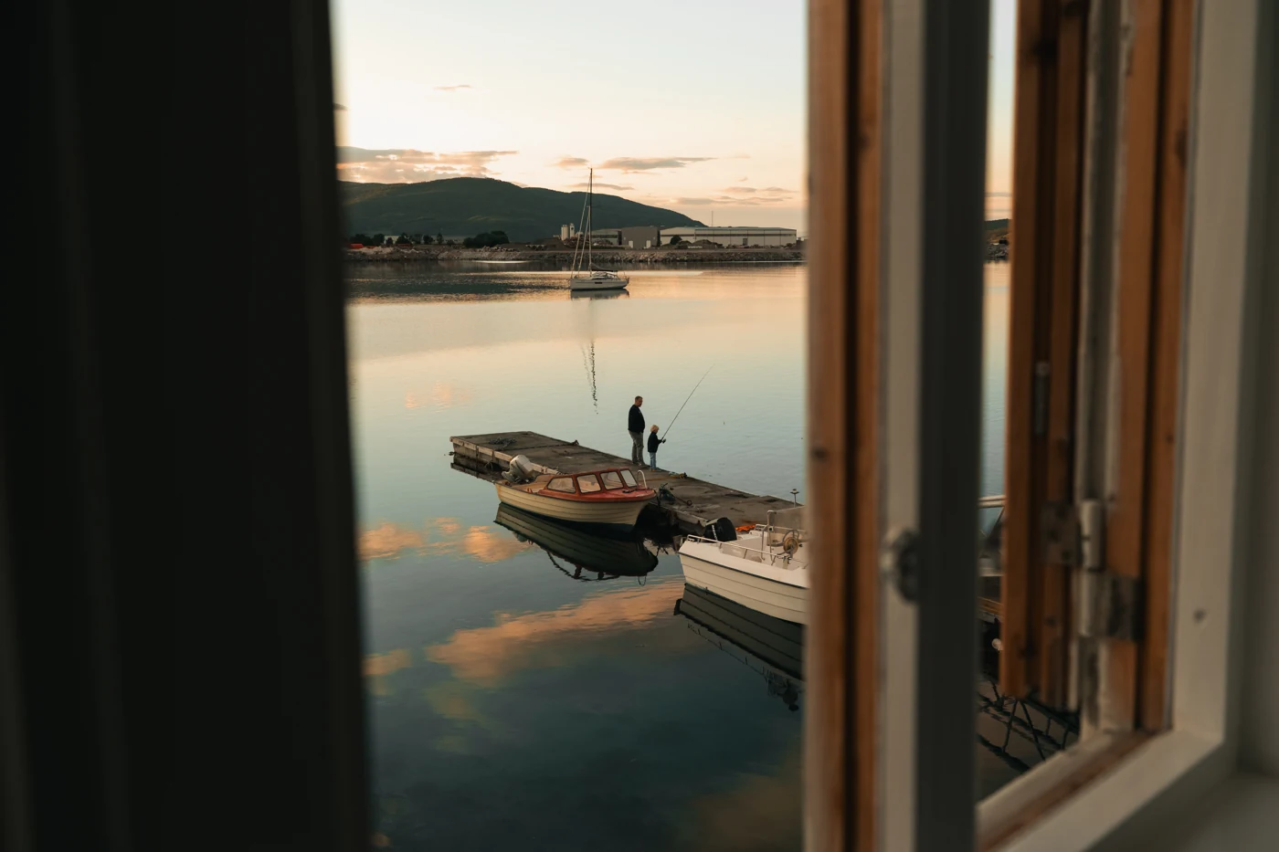 Un porto norvegese al tramonto, visto attraverso una finestra aperta